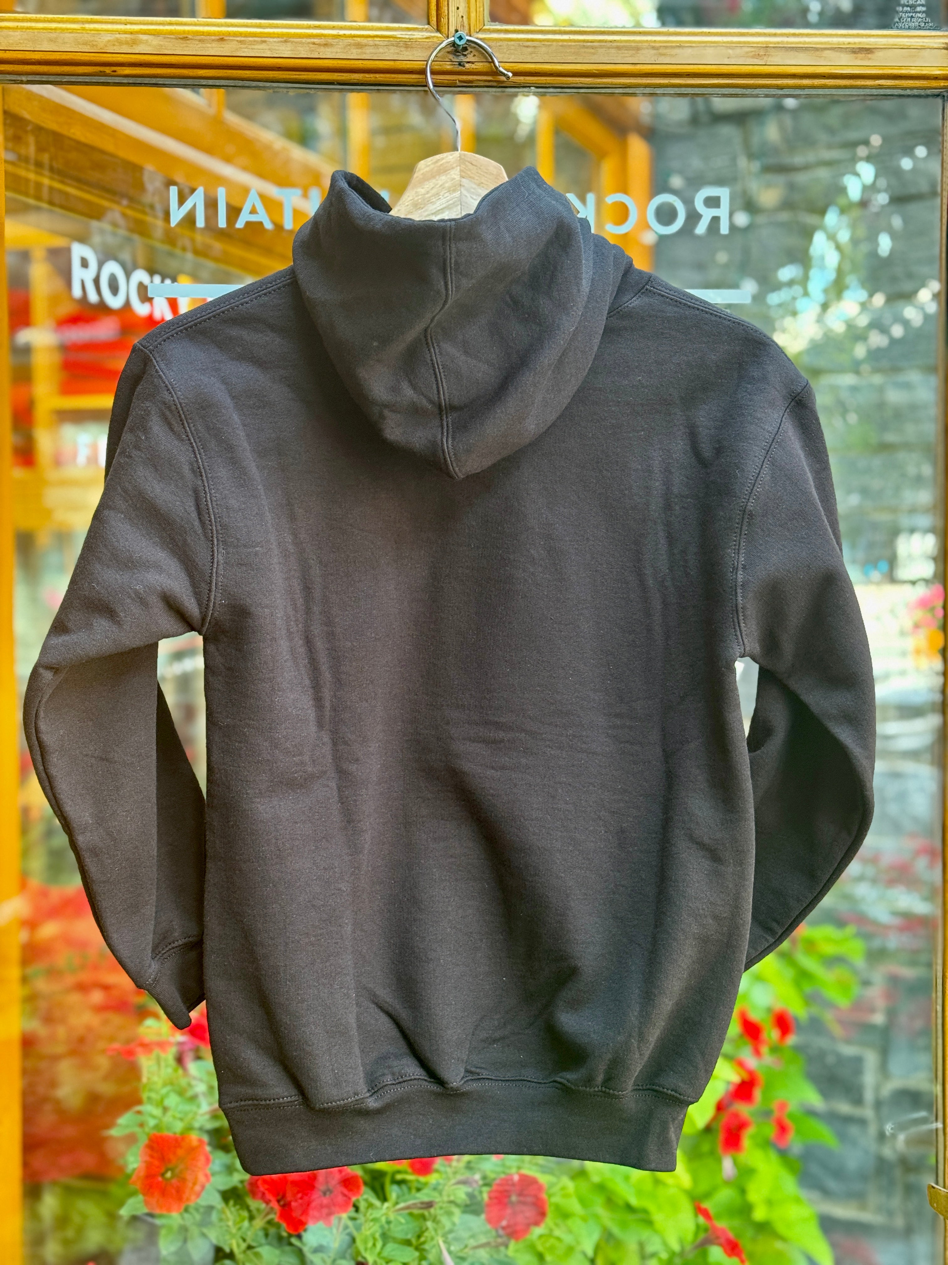 Kids Black hoodie on a hanger with a blurred store interior background
