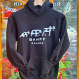 Black hoodie with white graphics and text 'Banff Canada' on a hanger in front of a glass door.