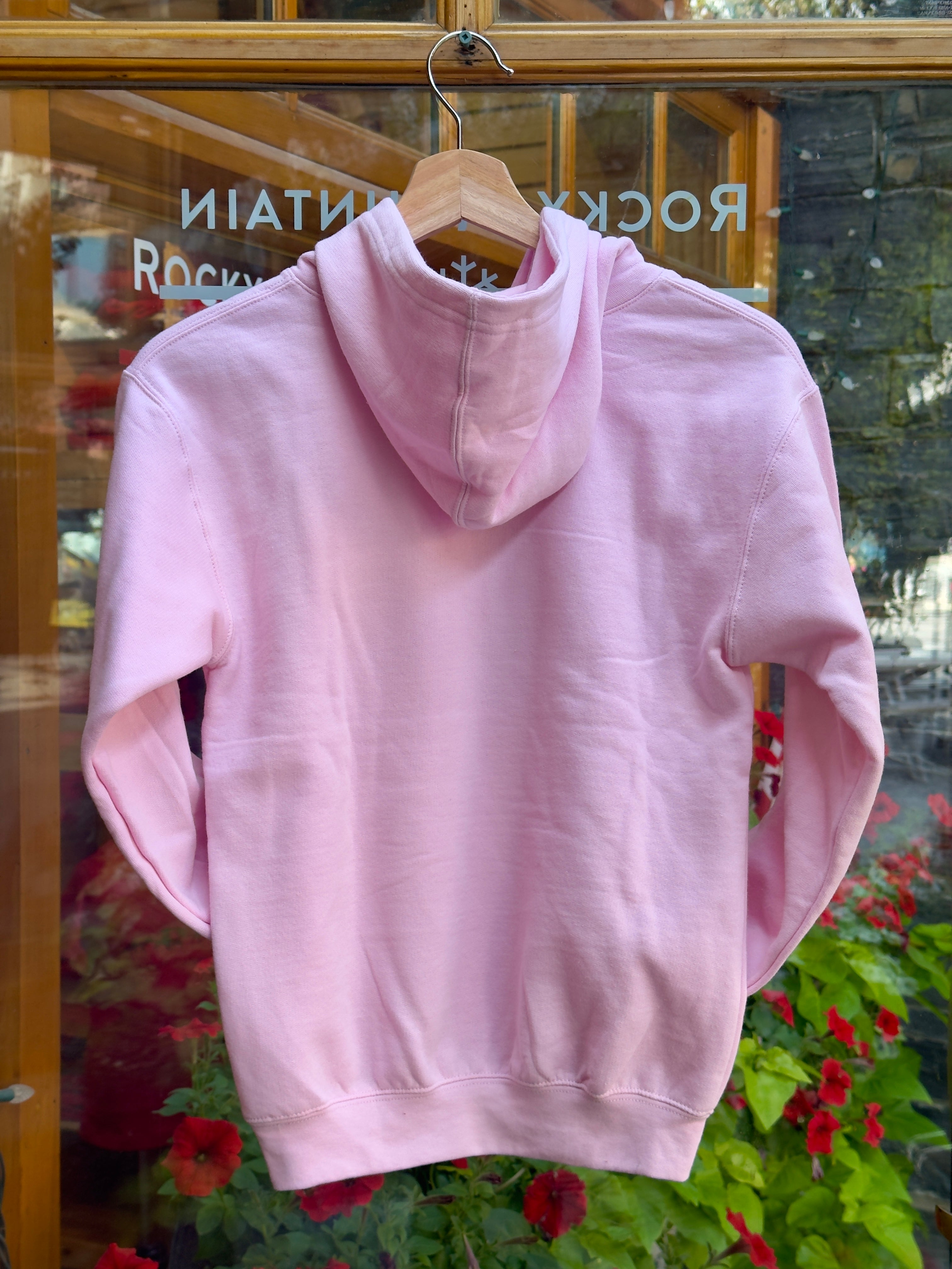 Kids pink hoodie on a hanger with a blurred background.