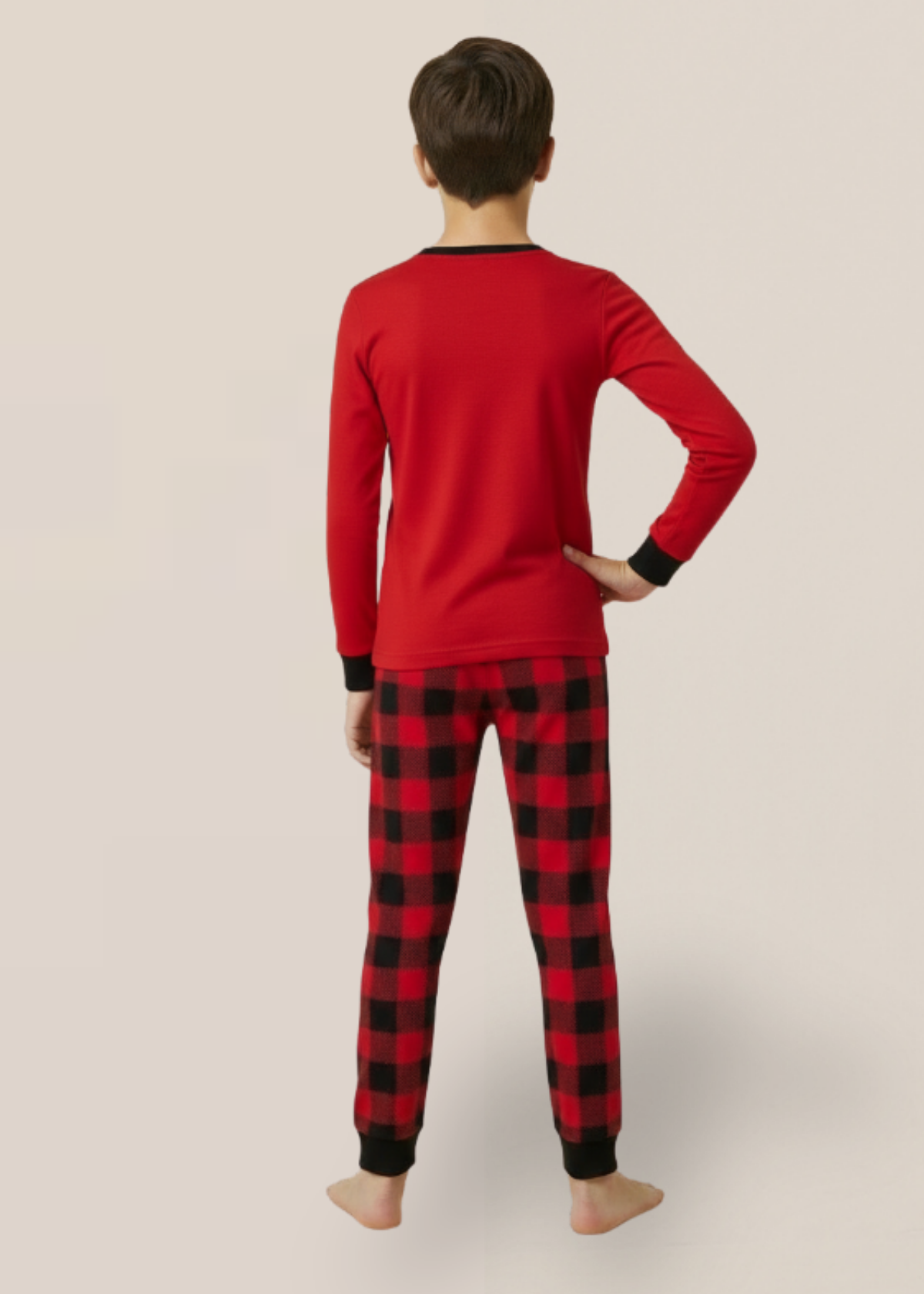 Kid wearing red long-sleeve top and black and red plaid pants on a beige background
