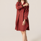 Woman wearing a red plaid nightshirt against a beige background