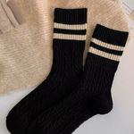 Black wool socks with beige stripes on a textured surface
