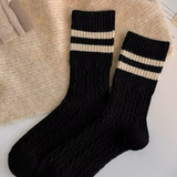 Black wool socks with beige stripes on a textured surface