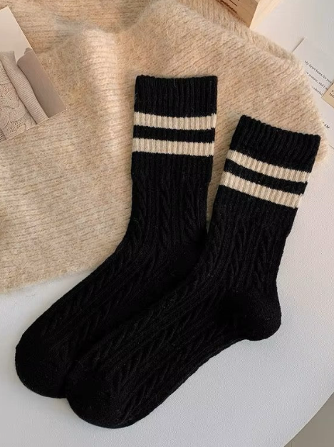 Black wool socks with beige stripes on a textured surface