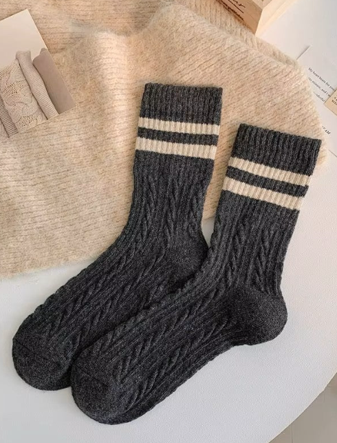 Pair of dark gray socks with white stripes on a textured surface