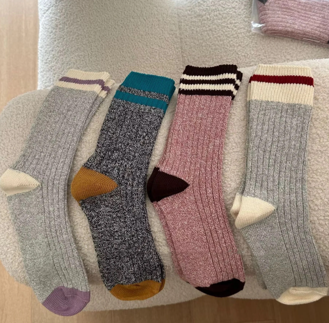 Four pairs of colorful socks arranged on a textured surface.