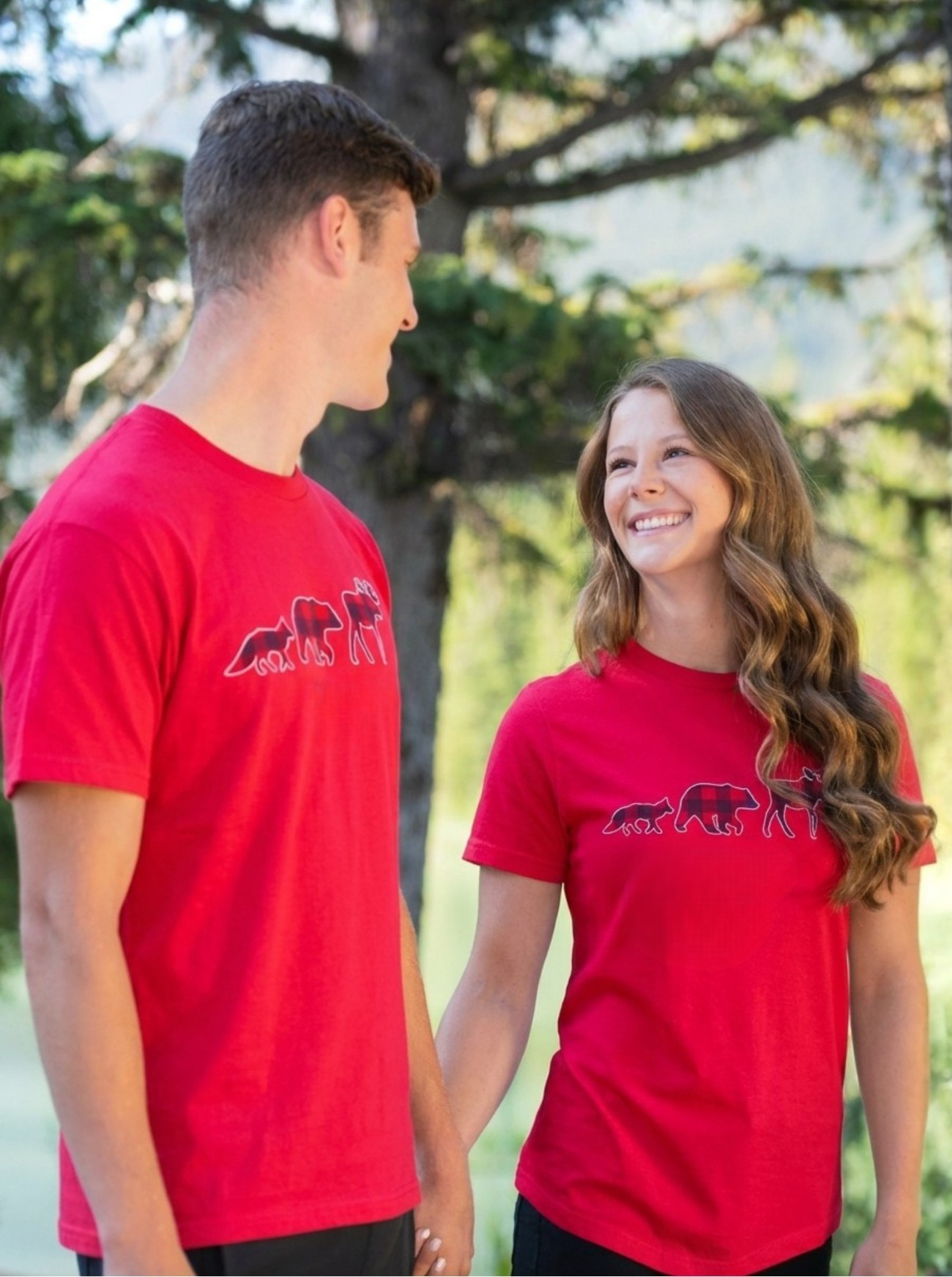 Two people wearing red t-shirts outdoors.