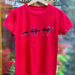 Red t-shirt with moose, bear and fox graphic on a hanger in front of a store window.