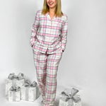 Woman wearing a pink and white checkered pajama set with wrapped gifts on a white background