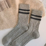 Pair of grey wool socks with black stripes on a textured surface.