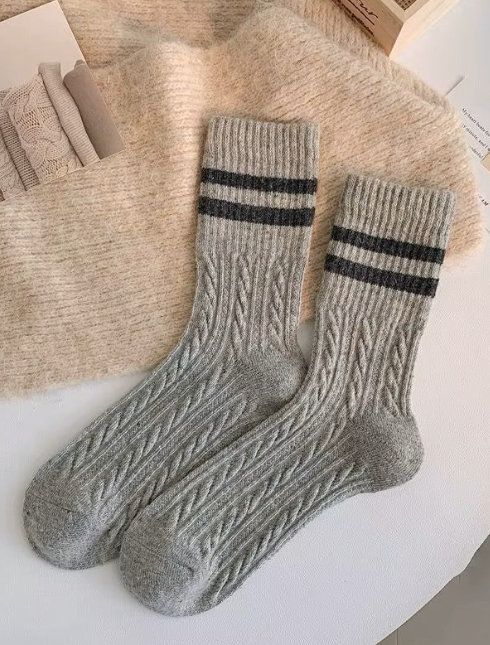 Pair of grey wool socks with black stripes on a textured surface.