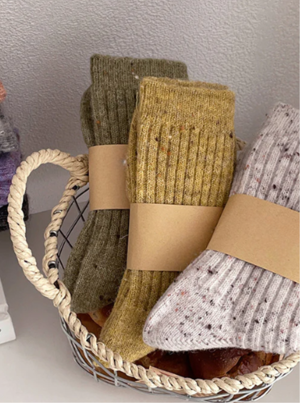 Basket with pairs of socks in various colors on a white surface.