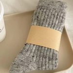 Gray wool socks with a beige band on a light surface