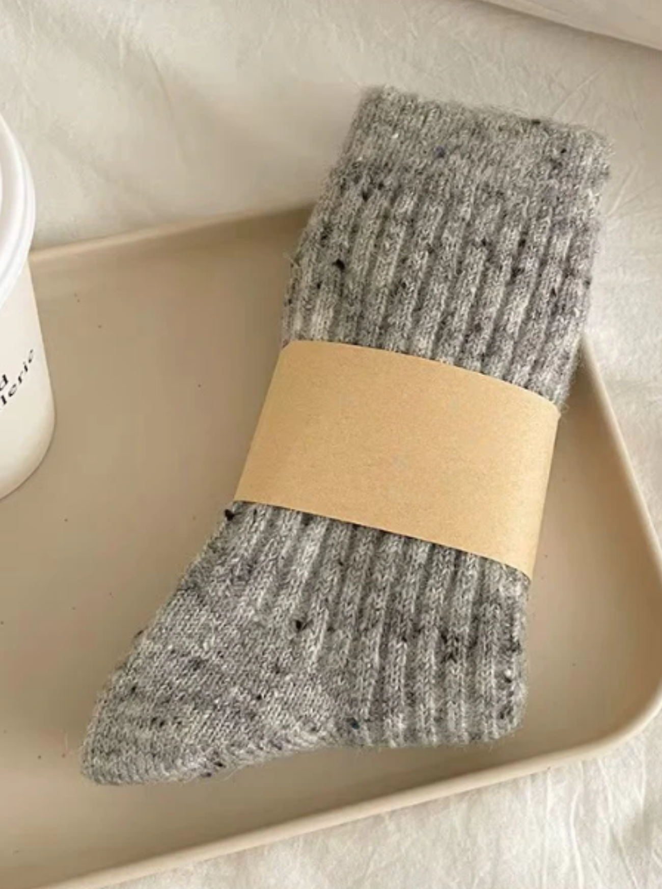 Gray wool socks with a beige band on a light surface