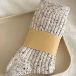 Pair of oatmeal wool socks with a beige band on a light background
