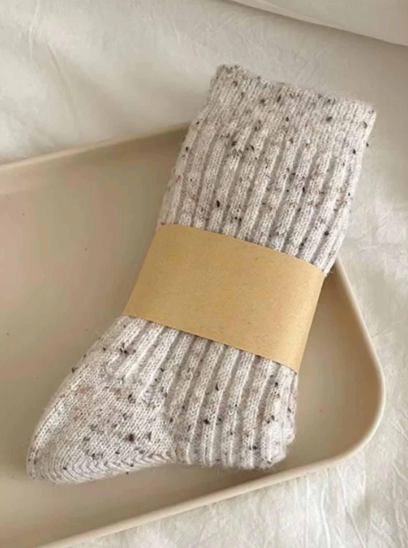 Pair of oatmeal wool socks with a beige band on a light background