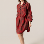 Woman wearing a red plaid nightshirt against a beige background