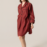 Woman wearing a red plaid nightshirt against a beige background