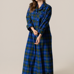 Woman wearing a blue and green plaid nightgown against a plain background