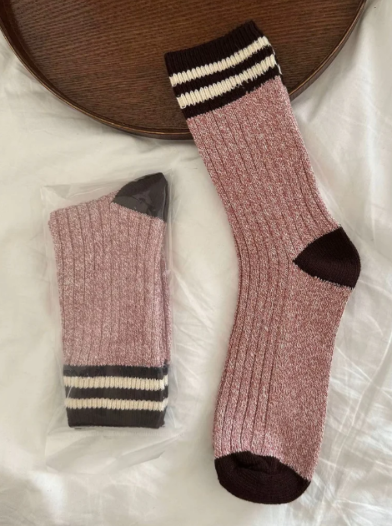 Pair of rose socks with black and white striped cuffs on a light surface.