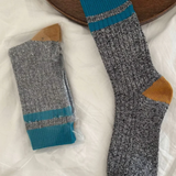 Pair of gray socks with blue and brown accents on a white surface.