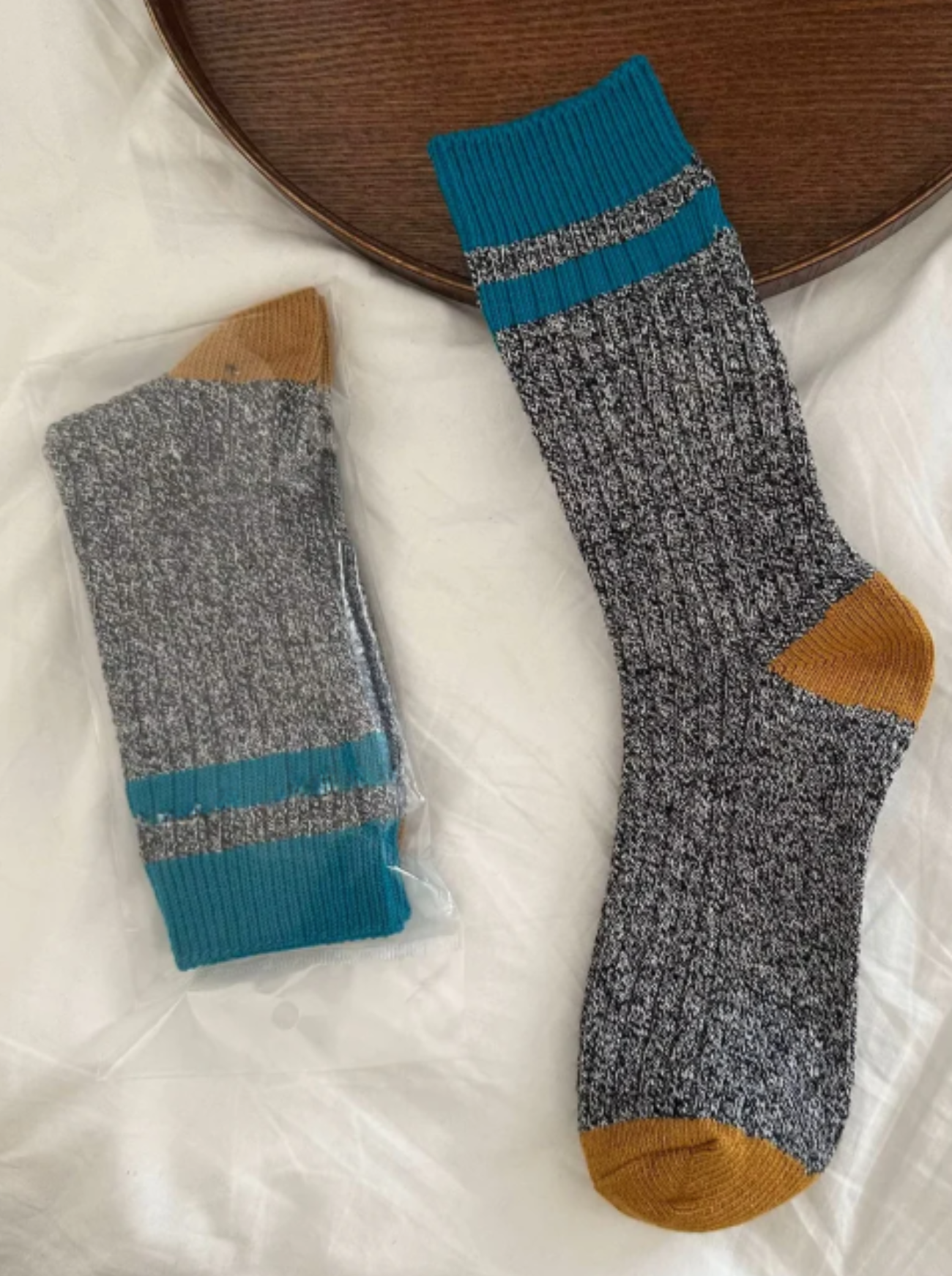 Pair of gray socks with blue and brown accents on a white surface.