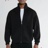 A man wearing a full zip black relaxed fit Canadian jacket with a soft stand collar and Canadian flag patch on the left sleeve.