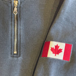 Gray jacket with a zipper and a red and white patch featuring a maple leaf.