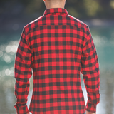 Person wearing a red and black plaid shirt with a blurred natural background