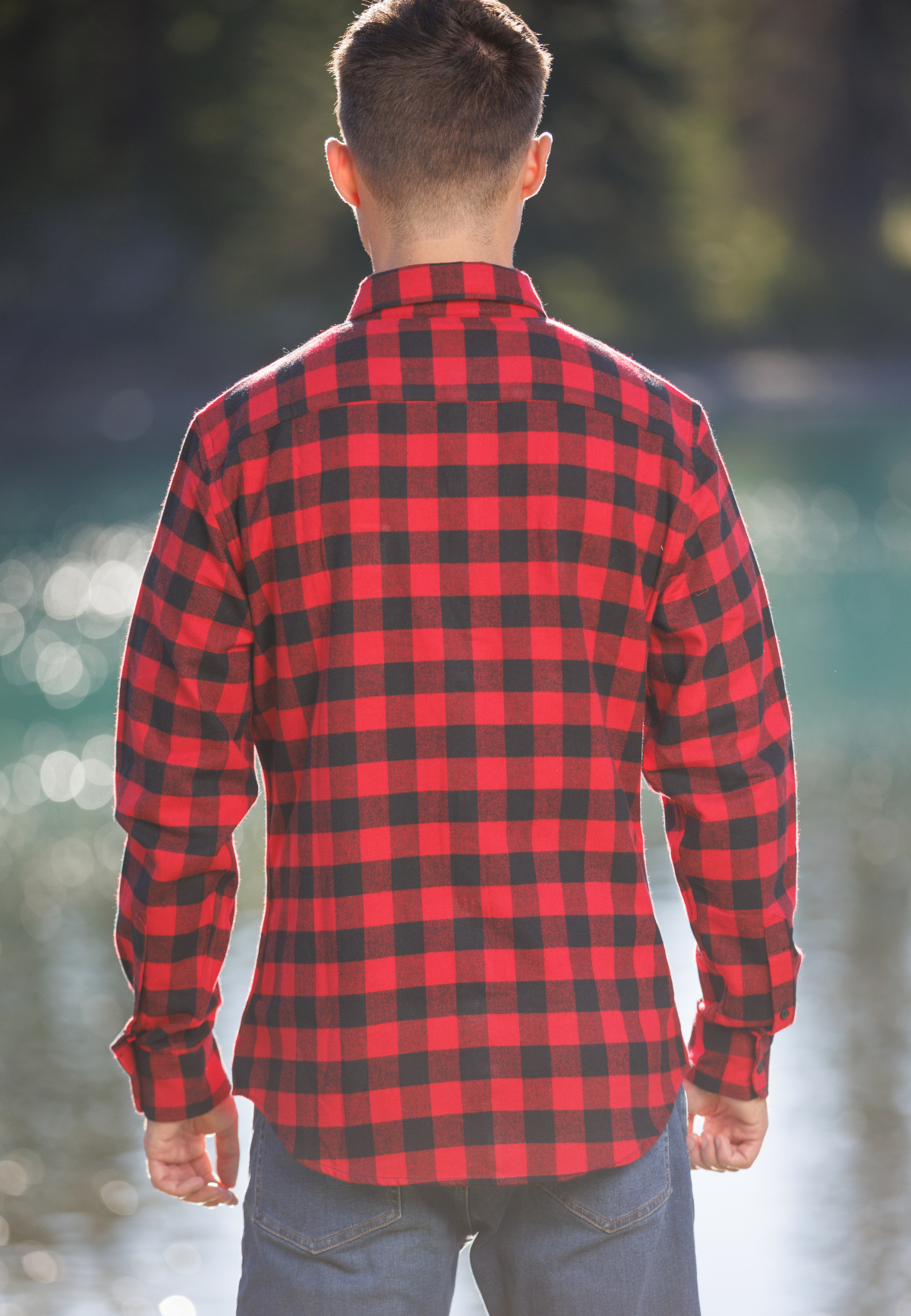 Person wearing a red and black plaid shirt with a blurred natural background