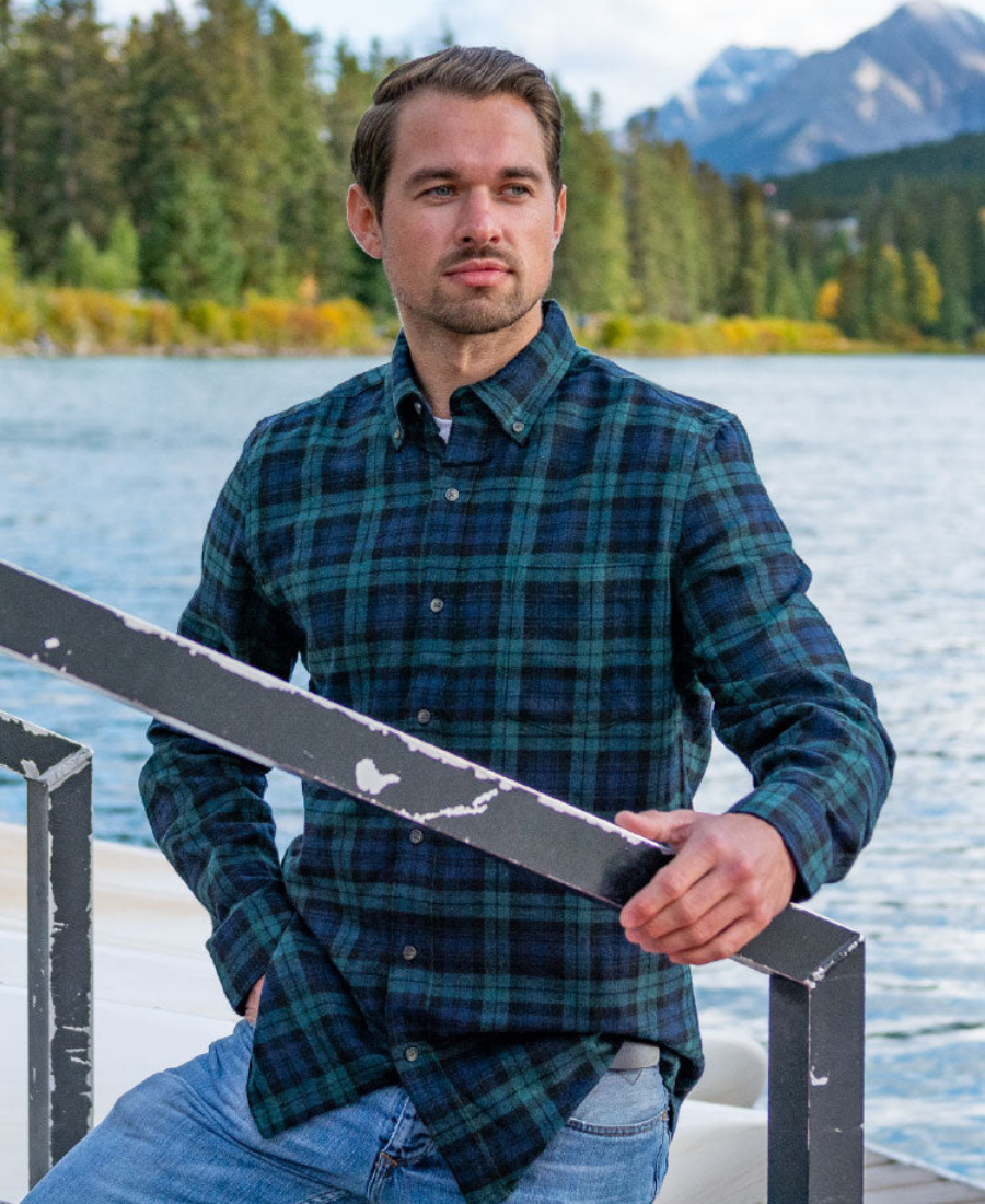 Man in a black watch flannel shirt on a dock with a scenic background in Banff National Park