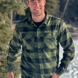 A man wearing a black and olive buffalo check flannel shirt with two flap breast pockets and a two button cuff.