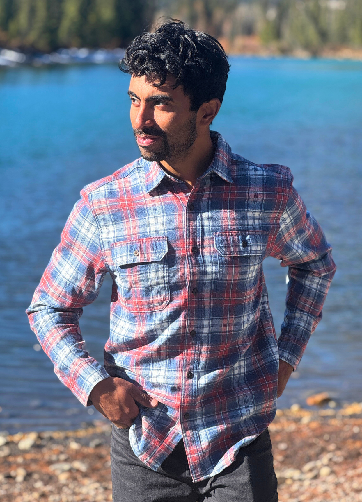 Man wearing a plaid flannel shirt by a river in Banff National Park
