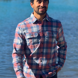 Man wearing a plaid flannel shirt standing by a body of water in Banff National Park