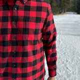 Close up of man wearing a classic Canadian red and black buffalo check button-down shirt with a single pocket on the chest.