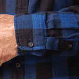 Close up of the cuff of long-sleeved marine blue and black buffalo check flannel shirt.