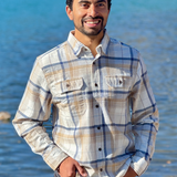 Man wearing a plaid flannel shirt standing by a body of water in Banff National Park