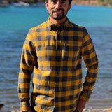 Man wearing a gold and grey checkered shirt standing by a river in Banff National Park.