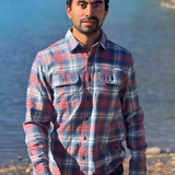 Man wearing a plaid flannel shirt standing by a river in Banff National Park