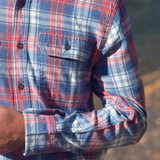Close-up of a person wearing a pink and blue plaid flannel shirt 