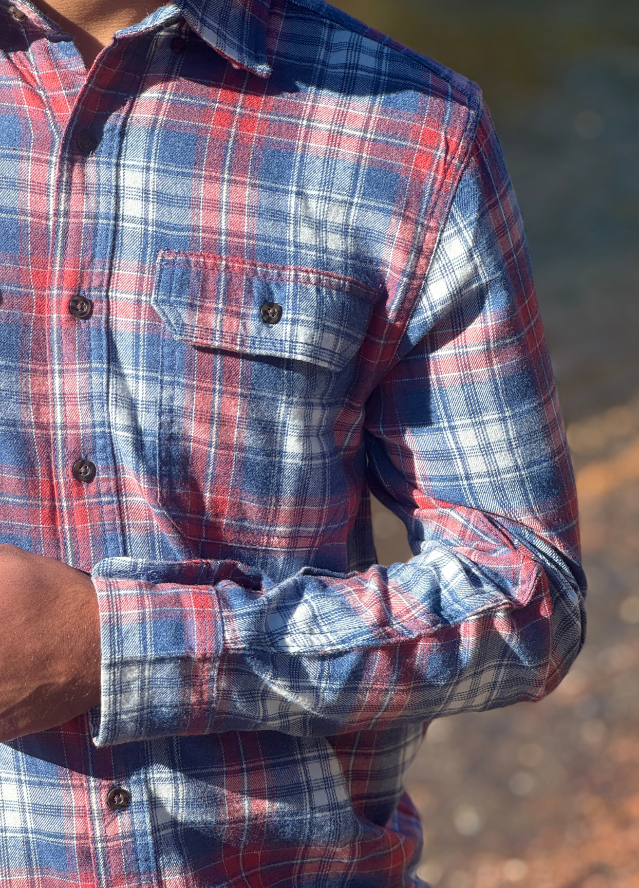 Close-up of a person wearing a pink and blue plaid flannel shirt 