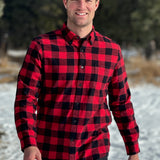 A man wearing a classic Canadian red and black buffalo check button-down shirt with a single pocket on the chest. This shot is taken in Banff National Park
