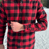 A man wearing a classic Canadian red and black buffalo check button-down shirt with a single pocket on the chest.