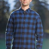 Man standing outdoors wearing long-sleeved marine blue and black buffalo check flannel shirt.
