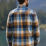 Man wearing a flannel shirt with a scenic background