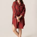 Woman wearing a red plaid shirt dress against a beige background