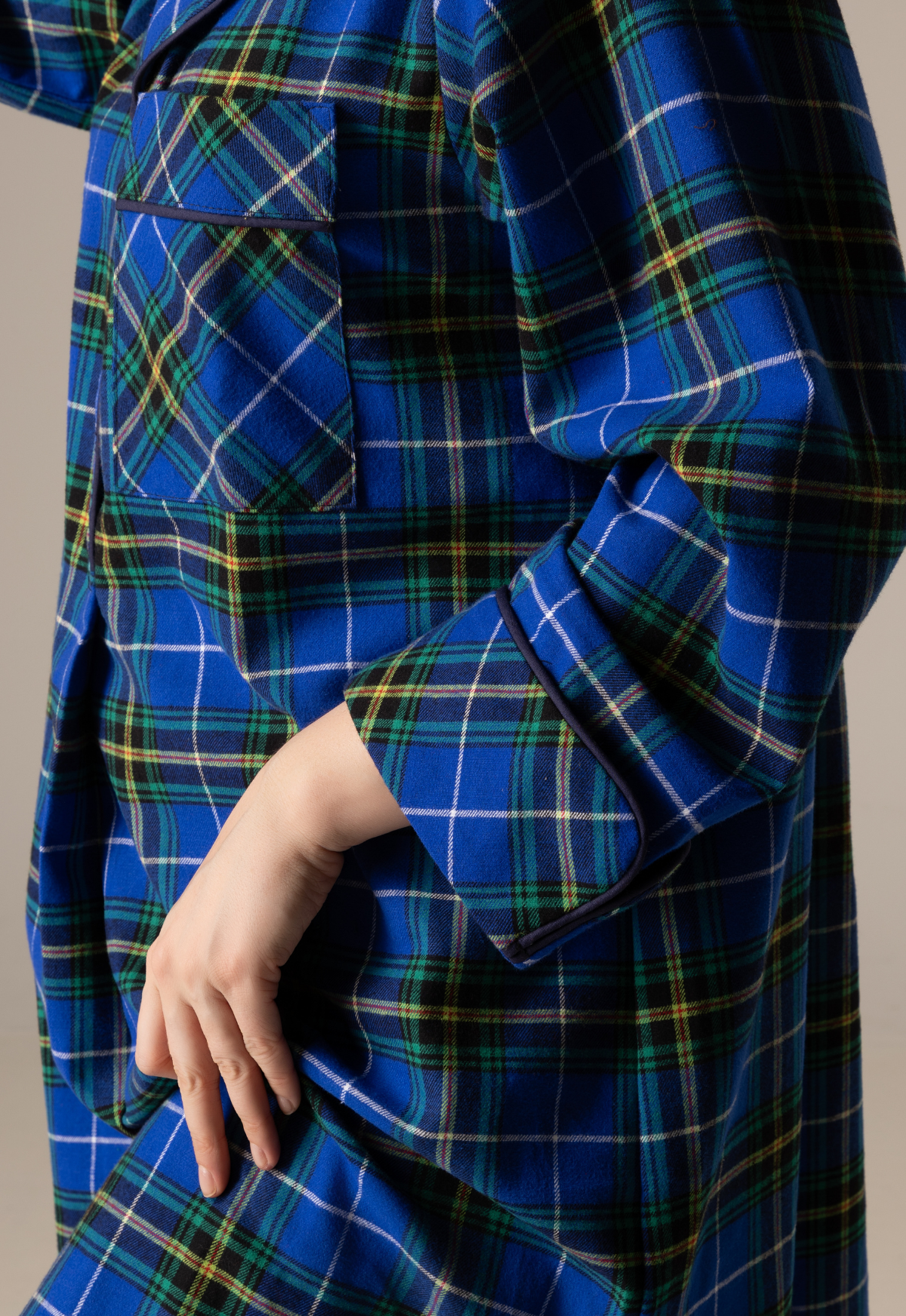 Blue plaid nightgown with a hand adjusting the collar against a neutral background