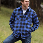 A man wearing a royal blue and black buffalo check padded flannel camping outdoor jacket with jeans.