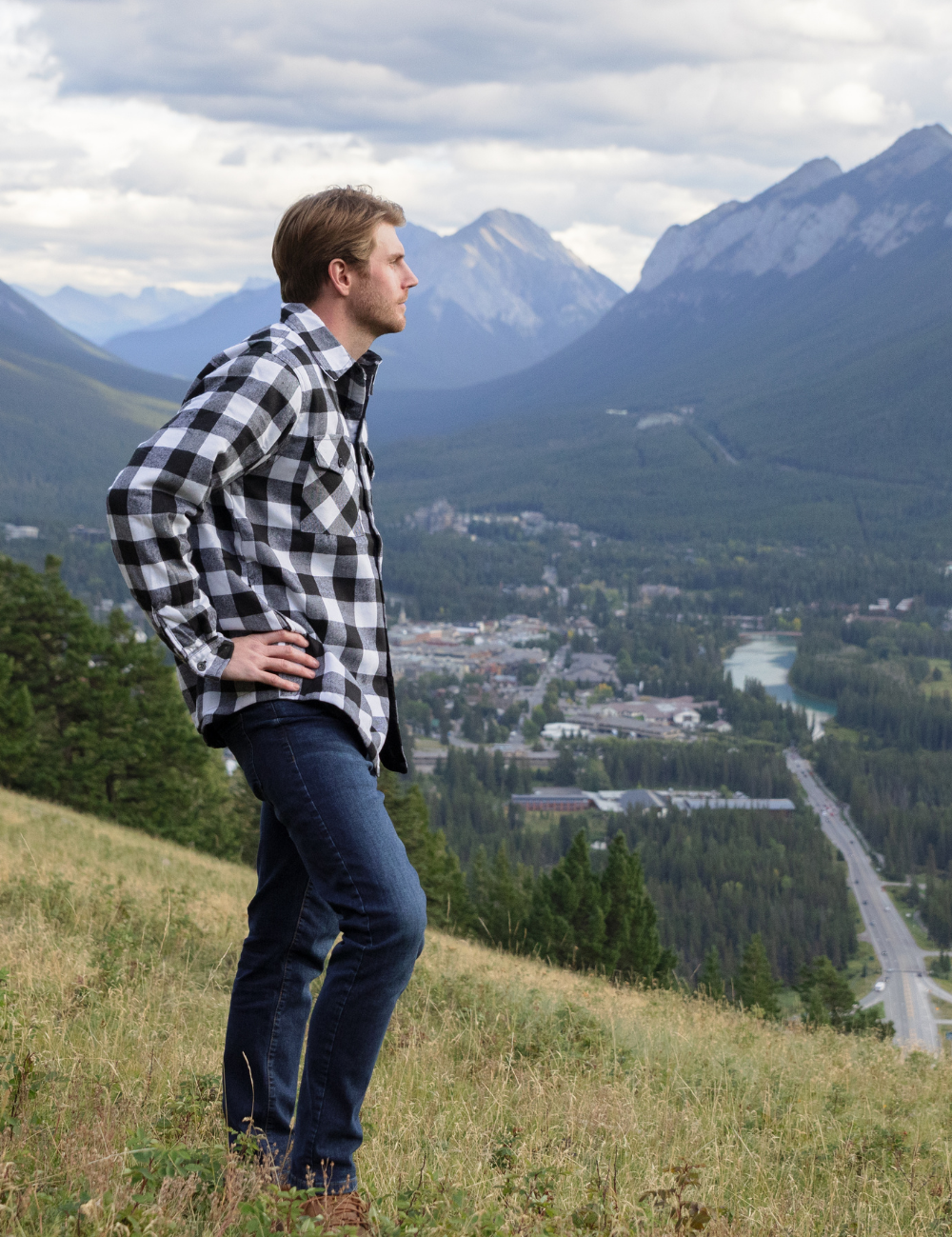 Person standing on a hill with mountains and a town in the background