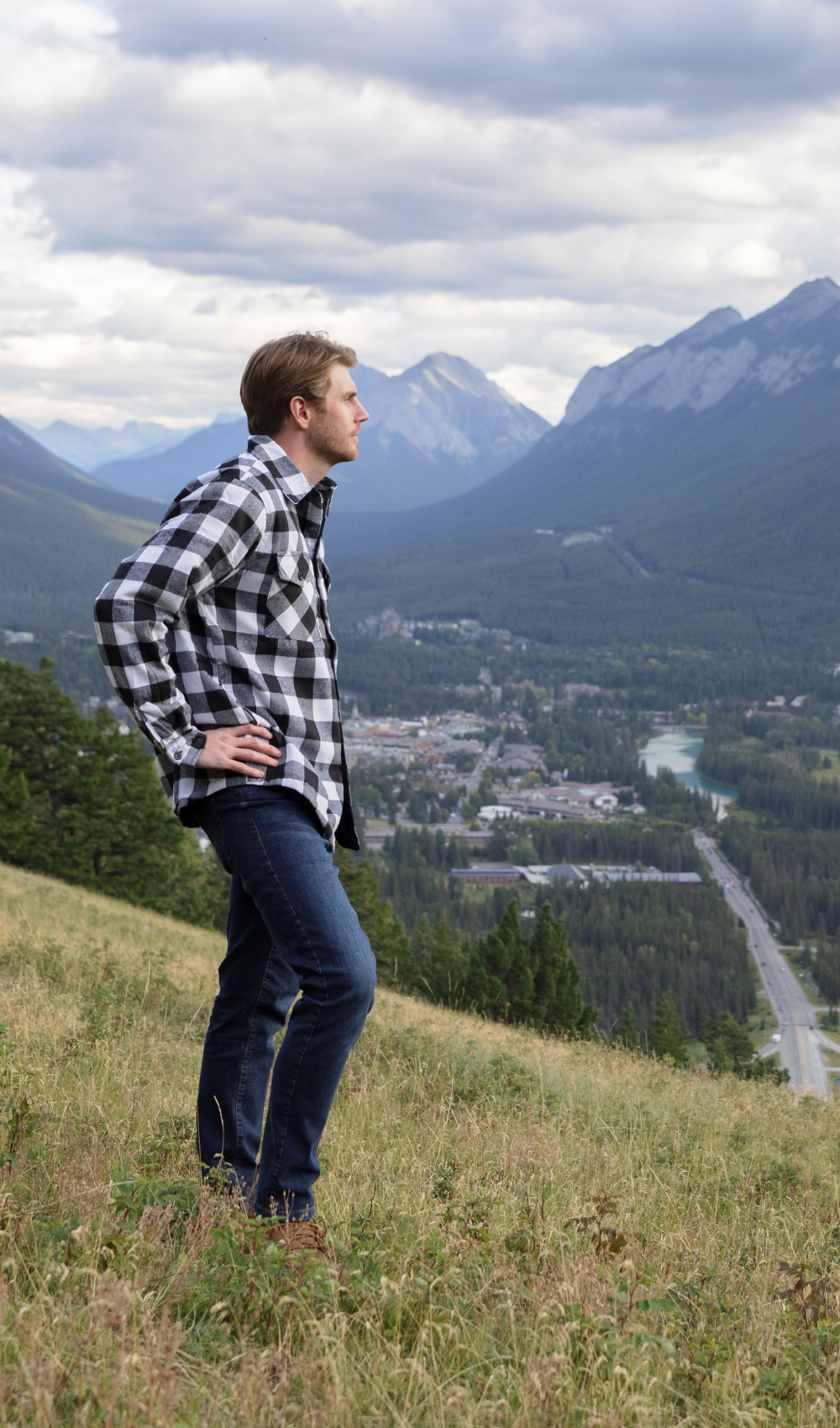 Person standing on a hill with mountains and a town in the background